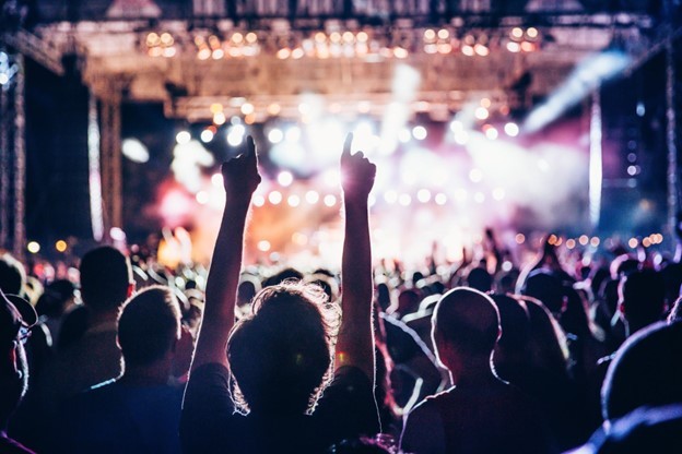Image of a crowd of people watching a rock concert, lights flashing on stage towards the viewer. Photo courtesy Microsoft 365 Stock Images